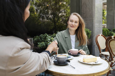 Geschäftspartner beim Händeschütteln mit Kaffeetassen auf dem Tisch eines Straßencafés - NDEF00843