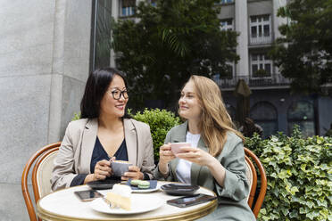 Lächelnde Geschäftspartner genießen einen Kaffee in einem Straßencafé - NDEF00850