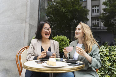 Geschäftspartner lachen und genießen einen Kaffee in einem Straßencafé - NDEF00851