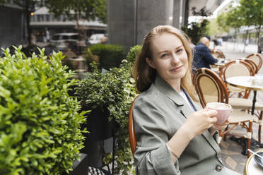 Junge Geschäftsfrau genießt Kaffee in einem Straßencafé - NDEF00855