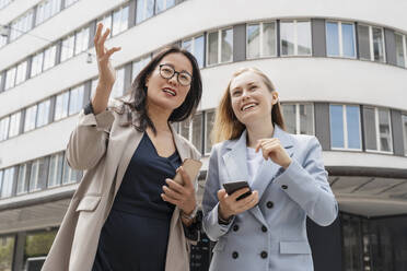 Businesswomen discussing with each other standing in front of building - NDEF00871