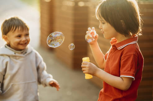 Playful brothers blowing soap bubbles - ANAF01588