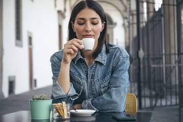 Frau sitzt und trinkt Kaffee in einem Café - JSRF02540