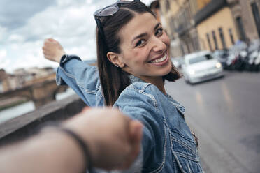 Smiling woman holding partner's hand on street - JSRF02542