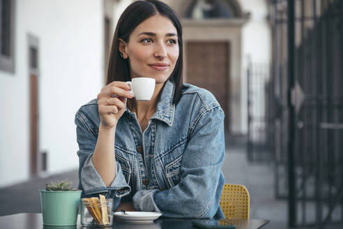 Lächelnde Frau in Jeansjacke bei einem Kaffee im Café - JSRF02543