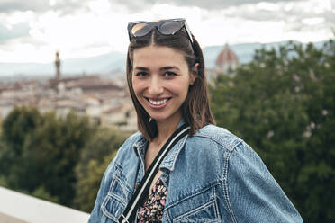 Smiling woman standing above the city - JSRF02565