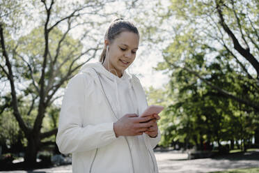 Teenager-Mädchen benutzt Smartphone im Park - AAZF00750