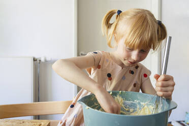 Mädchen, das zu Hause Kuchenteig in einer Schüssel verrührt - IHF01404