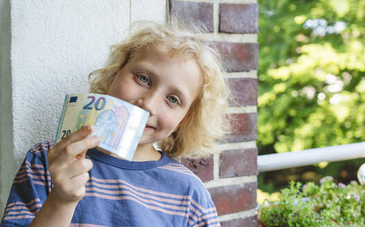Lächelnder Junge zeigt Geld an der Wand - IHF01410
