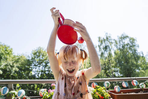 Cheerful girl pouring water on head in balcony - IHF01421