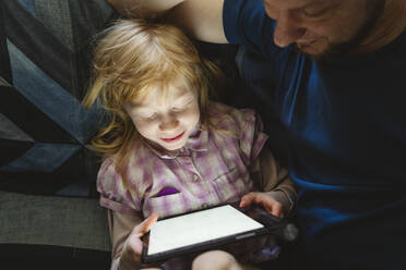 Daughter studying through tablet PC sitting with father - IHF01426