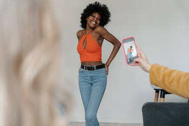 Eine Frau macht mit ihrem Smartphone ein Selfie von ihrem Freund zu Hause. - EHAF00053