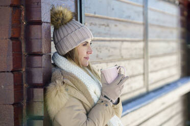 Lächelnde Frau beim Kaffeetrinken im Winter - JSMF02775
