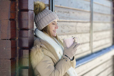Smiling woman enjoying coffee in winter holidays - JSMF02776