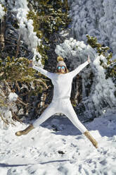 Smiling woman jumping in winter snow - JSMF02781