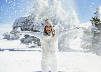 Smiling woman with mouth open standing in winter snow - JSMF02792