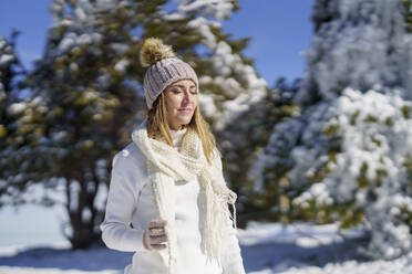 Smiling woman with eyes closed standing in winter snow - JSMF02800