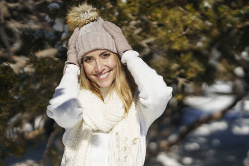 Lächelnde Frau beim Einstellen der Mütze im Winter - JSMF02801