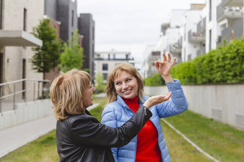 Happy daughter giving key to mother near residential area - IHF01456