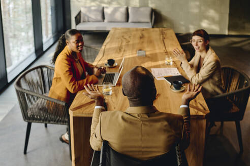 Businessman discussing with coworkers at conference table in convention center - DSHF00854