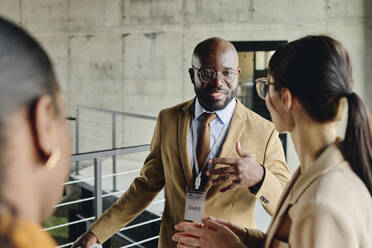 Businessman talking with colleague at convention center - DSHF00876