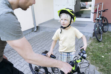 Lächelnder Junge mit Vater, der ein Fahrrad am Fußweg hält - NJAF00430