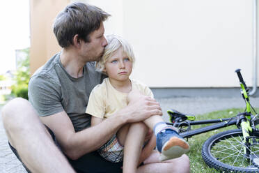 Vater küsst und pflegt Sohn, der vom Fahrrad gefallen ist - NJAF00434