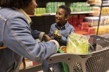 Lächelnder Junge beim Einkaufen mit seiner Mutter im Supermarkt - JCCMF10494