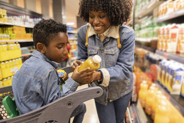 Glückliche Mutter kauft mit ihrem Sohn im Supermarkt ein - JCCMF10495
