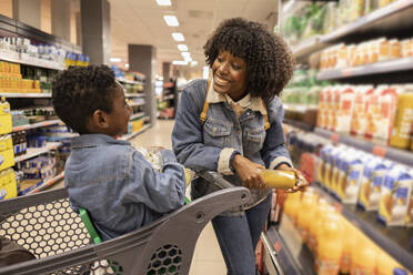 Glückliche junge Frau, die mit ihrem Sohn im Supermarkt einkauft - JCCMF10496