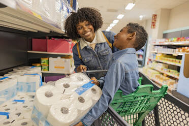 Glückliche Mutter und Sohn kaufen Toilettenpapier im Supermarkt - JCCMF10505