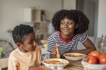 Lächelnde Frau mit Sohn beim gemeinsamen Essen zu Hause - JCCMF10587