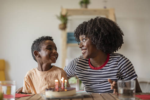 Glückliche Mutter feiert den Geburtstag ihres Sohnes mit Kuchen zu Hause - JCCMF10591