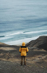 Man standing on volcanic landscape in front of sea at Fuerteventura - RSGF00942