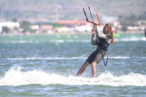 Glücklicher Sportler beim Kiteboarden im Meer an einem sonnigen Tag - DMHF00035