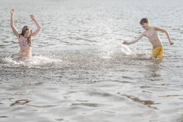 Glücklicher Junge und Mädchen spielen und genießen im Meer - ANAF01592