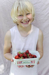 Smiling girl holding fresh strawberries from garden - GISF00964