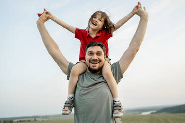 Cheerful father carrying son on shoulders at field - ANAF01608