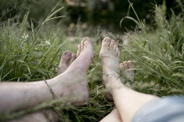 Paar entspannt sich zusammen im Gras auf einem Feld - ANAF01625