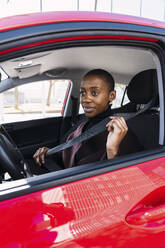 Thoughtful woman adjusting seat belt in car - PNAF05482