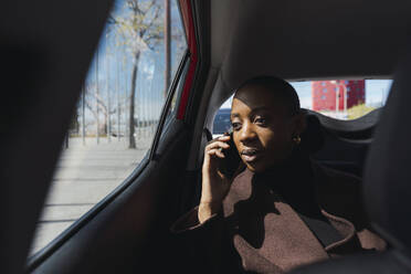 Geschäftsfrau, die im Auto mit einem Smartphone telefoniert - PNAF05491
