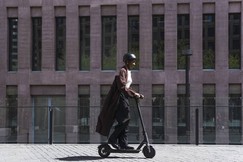 Businesswoman riding electric push scooter on sunny day - PNAF05554