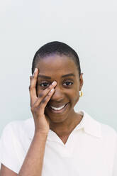 Happy woman touching face against white background - PNAF05556