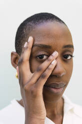 Young woman touching face against white background - PNAF05557