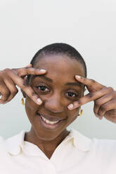 Smiling young woman gesturing and touching face against white background - PNAF05559