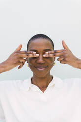 Smiling woman covering eyes against white background - PNAF05568