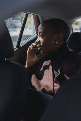 Nachdenkliche Geschäftsfrau, die im Auto mit ihrem Smartphone telefoniert - PNAF05575