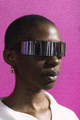 Geschäftsfrau mit einer intelligenten Brille vor einer rosa Wand - PNAF05583