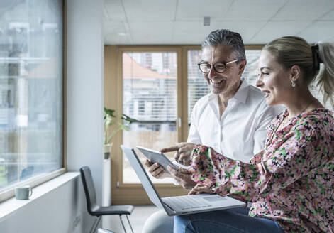 Geschäftsfrau und Geschäftsmann arbeiten an einem Tablet-PC im Büro - UUF29201