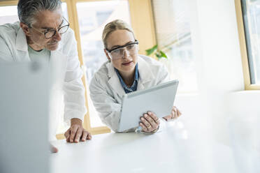 Wissenschaftler in Laborkitteln bei der Arbeit an einem Tablet-Computer im Labor - UUF29207